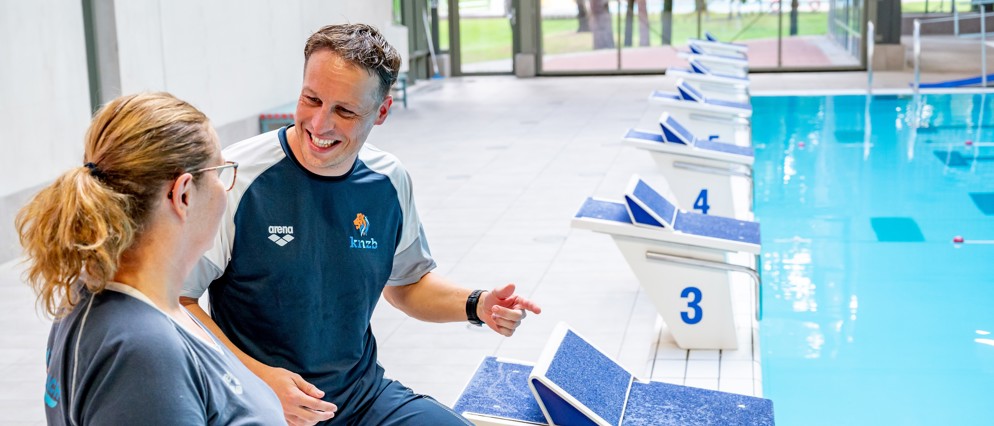 Twee trainers die met elkaar overleggen